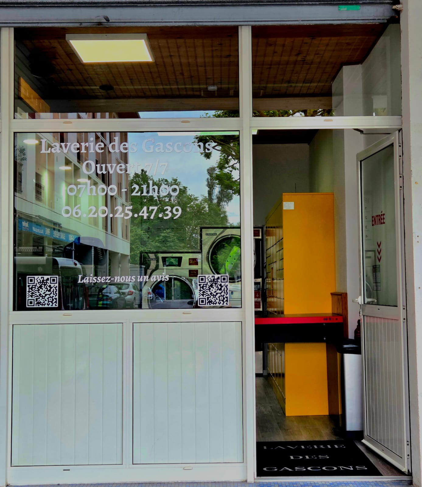 Devanture de la Laverie Des Gascons — façade vitrée avec horaires et QR code